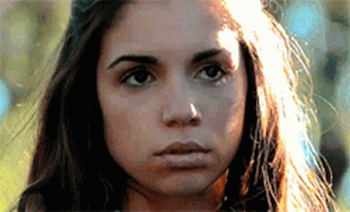 a close up of a woman 's face with the sun shining on her hair