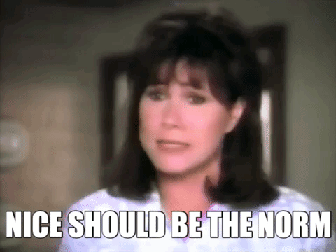 A Close Up Of A Woman 'S Face With The Words " Nice Should Be The Norm " Written Below Her . GIF