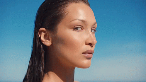 A Close Up Of A Woman 'S Face With Wet Hair Against A Blue Sky GIF
