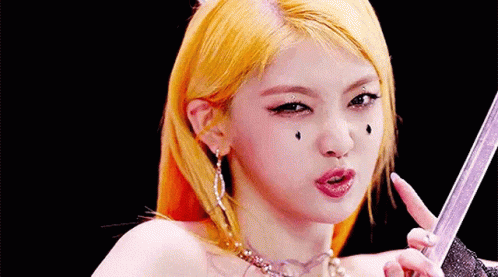 A Close Up Of A Woman 'S Face With Yellow Hair Holding A Sword . GIF