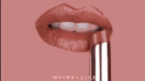 A Close Up Of A Woman 'S Lips With A Maybelline Lipstick Sticking Out Of Them . GIF
