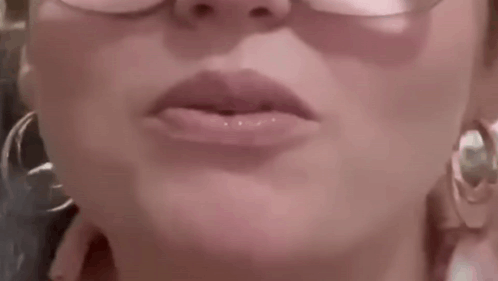 A Close Up Of A Woman 'S Lips With Glasses And Hoop Earrings . GIF