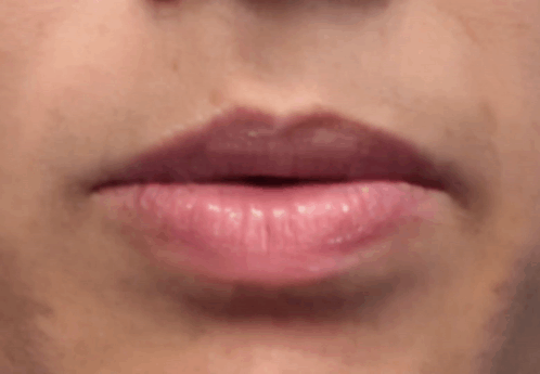 A Close Up Of A Woman 'S Lips With Pink Lipstick And Teeth . GIF