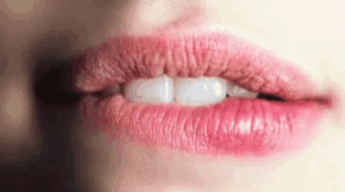 A Close Up Of A Woman 'S Mouth With Pink Lips And White Teeth . GIF