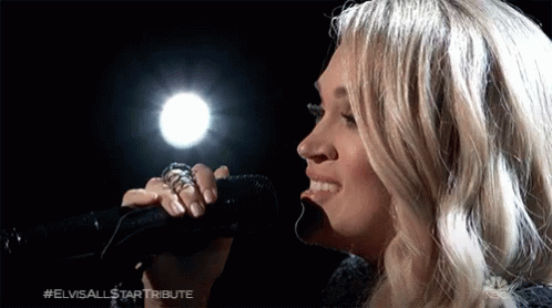 A Close Up Of A Woman Singing Into A Microphone GIF