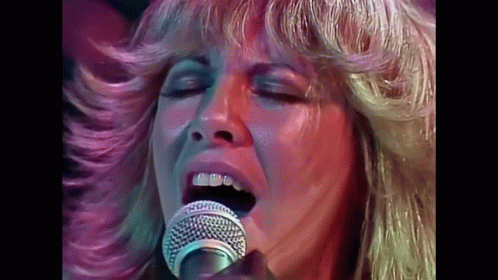 A Close Up Of A Woman Singing Into A Microphone GIF
