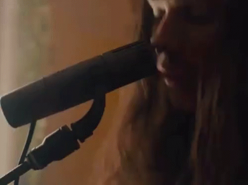 A Close Up Of A Woman Singing Into A Microphone GIF