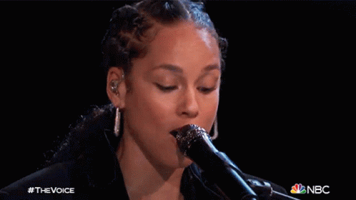 A Close Up Of A Woman Singing Into A Microphone With The Nbc Logo In The Corner GIF