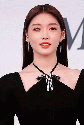 A Close Up Of A Woman Wearing A Black Dress With A Bow Around Her Neck . GIF