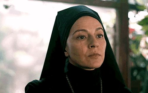 A Close Up Of A Woman Wearing A Black Veil And A Necklace GIF