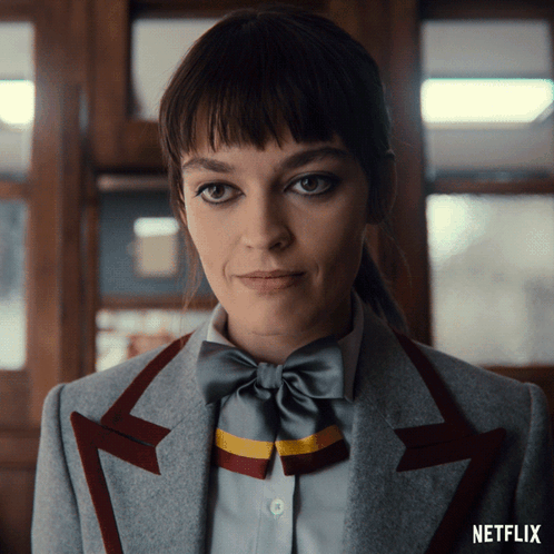 A Close Up Of A Woman Wearing A Bow Tie And A Netflix Logo On The Bottom GIF