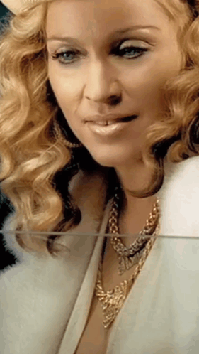 A Close Up Of A Woman Wearing A Fur Coat And Gold Necklace GIF