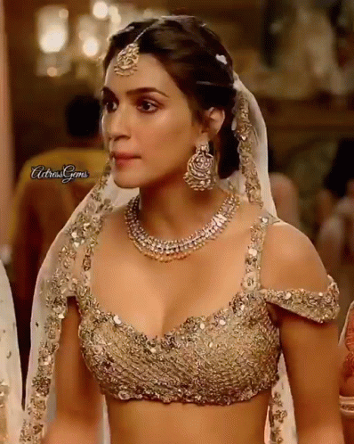A Close Up Of A Woman Wearing A Gold Top And A Necklace . GIF