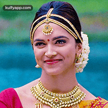A Close Up Of A Woman Wearing A Necklace And A Headpiece Smiling . GIF