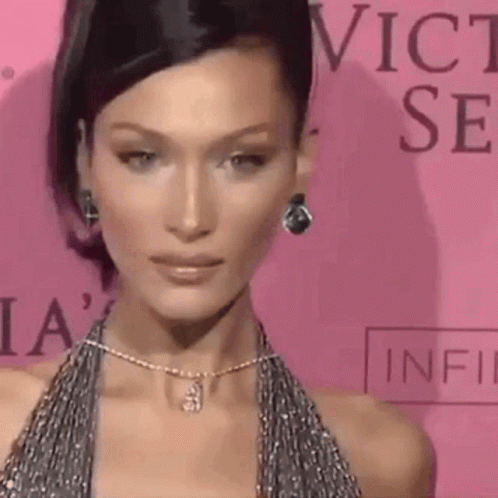 A Close Up Of A Woman Wearing A Necklace And Earrings On A Pink Carpet . GIF