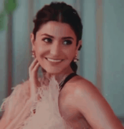 A Close Up Of A Woman Wearing A Pink Dress And Earrings Smiling . GIF