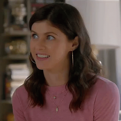 A Close Up Of A Woman Wearing A Pink Shirt , Necklace , And Hoop Earrings . GIF