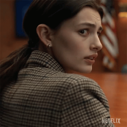 A Close Up Of A Woman Wearing A Plaid Jacket And Earrings . GIF