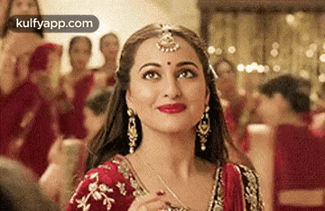 A Close Up Of A Woman Wearing A Red And Gold Dress And Earrings . GIF