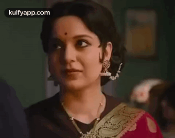A Close Up Of A Woman Wearing A Red Saree And Gold Earrings . GIF