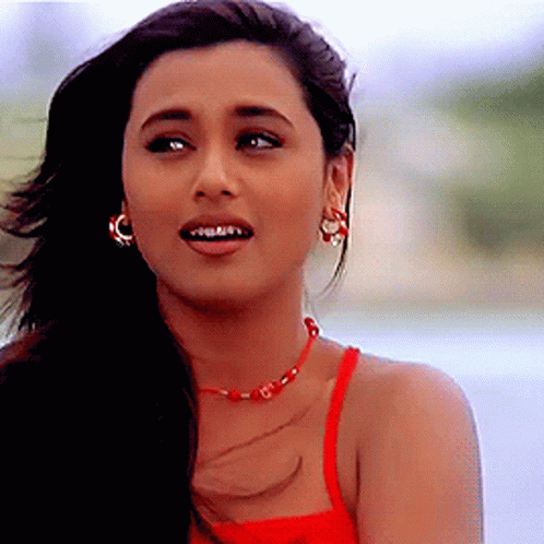 A Close Up Of A Woman Wearing A Red Tank Top And Earrings GIF