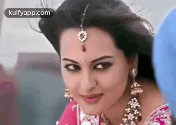 A Close Up Of A Woman Wearing A Saree And Earrings . GIF