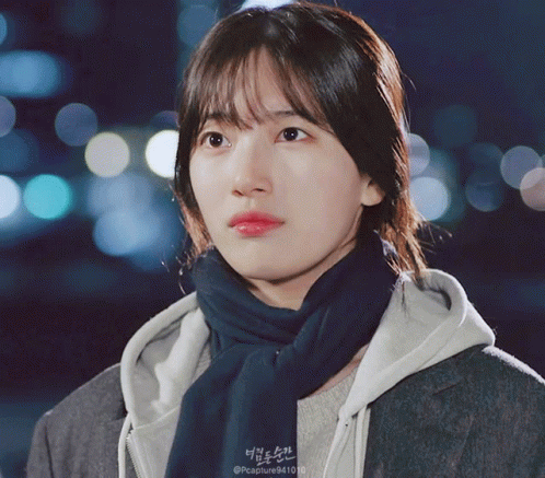 A Close Up Of A Woman Wearing A Scarf And A Hoodie That Says Capture9410 GIF