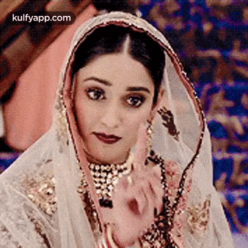 A Close Up Of A Woman Wearing A Veil And A Necklace . GIF