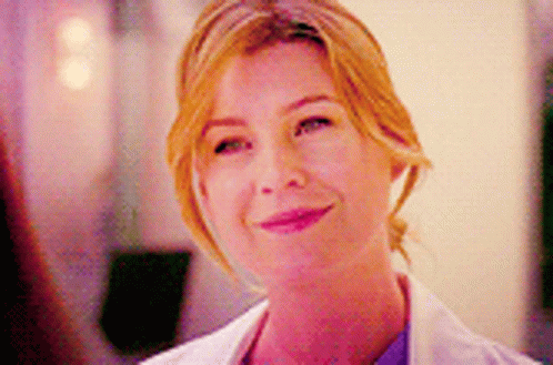 A Close Up Of A Woman Wearing A White Lab Coat And Smiling . GIF