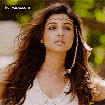 A Close Up Of A Woman Wearing A White Top And A Headband . GIF