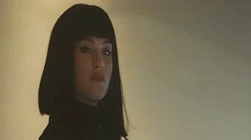 A Close Up Of A Woman Wearing A Wig And A Black Jacket . GIF