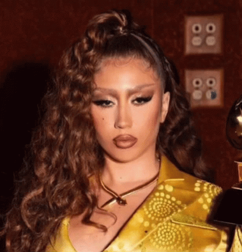 A Close Up Of A Woman Wearing A Yellow Dress And A Gold Necklace Holding A Trophy . GIF