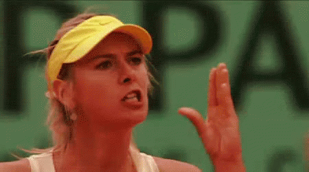 A Close Up Of A Woman Wearing A Yellow Visor And A White Tank Top On A Tennis Court . GIF