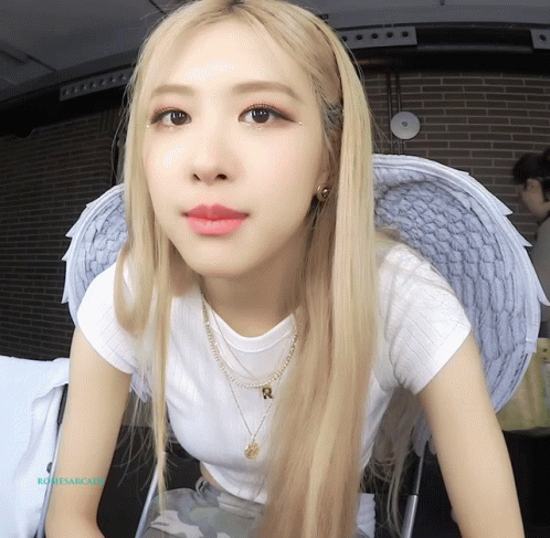 A Close Up Of A Woman Wearing Angel Wings And A Necklace With The Letter R On It GIF