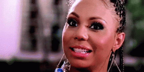 A Close Up Of A Woman Wearing Braids And Earrings Smiling . GIF