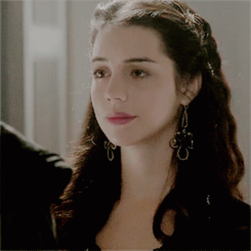 A Close Up Of A Woman Wearing Earrings And A Braided Hairstyle GIF