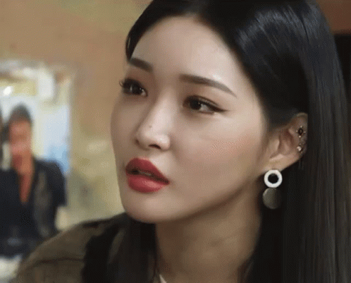 A Close Up Of A Woman Wearing Earrings And Red Lipstick Making A Funny Face . GIF