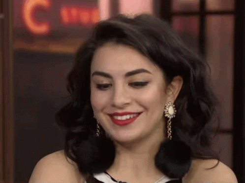 A Close Up Of A Woman Wearing Earrings And Red Lipstick Smiling . GIF