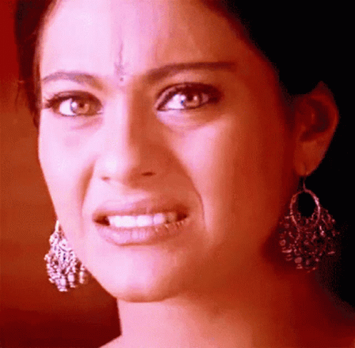 A Close Up Of A Woman Wearing Earrings Making A Face GIF
