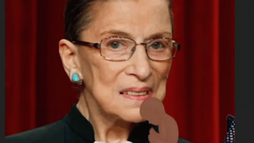 A Close Up Of A Woman Wearing Glasses And A Black Suit GIF