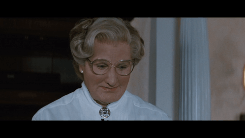 A Close Up Of A Woman Wearing Glasses And A Necklace GIF