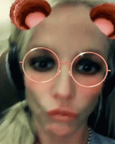 A Close Up Of A Woman Wearing Glasses And Headphones Making A Face GIF