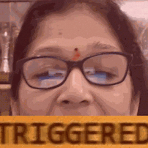 A Close Up Of A Woman Wearing Glasses And Holding A Sign That Says Triggered . GIF