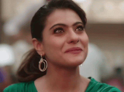 A Close Up Of A Woman Wearing Hoop Earrings And A Green Top GIF