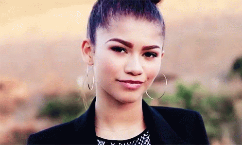 A Close Up Of A Woman Wearing Hoop Earrings And A Jacket GIF