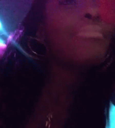 A Close Up Of A Woman Wearing Hoop Earrings And A Necklace With The Letter C On It GIF