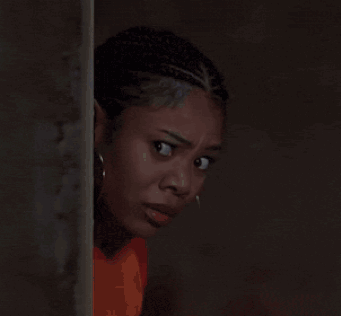 A Close Up Of A Woman Wearing Hoop Earrings And An Orange Shirt GIF