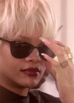 A Close Up Of A Woman Wearing Sunglasses And A Ring GIF