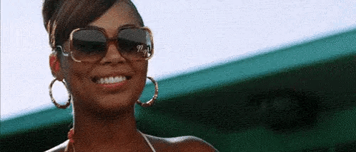 A Close Up Of A Woman Wearing Sunglasses And Hoop Earrings . GIF