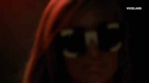 A Close Up Of A Woman Wearing Sunglasses And Hoop Earrings . GIF